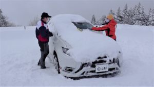 雪道走行前の準備で、車に積もった雪を払うところ。
